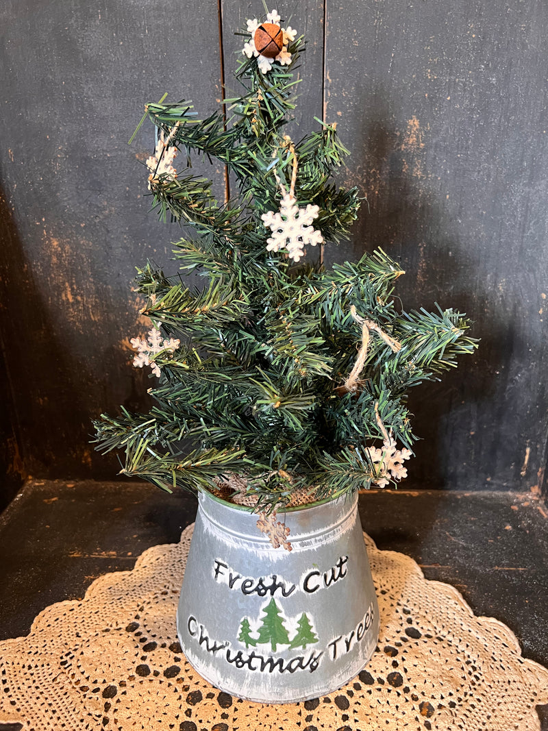 Tree In Fresh Cut Tree Bucket W/ Bell And Snowflake Topper